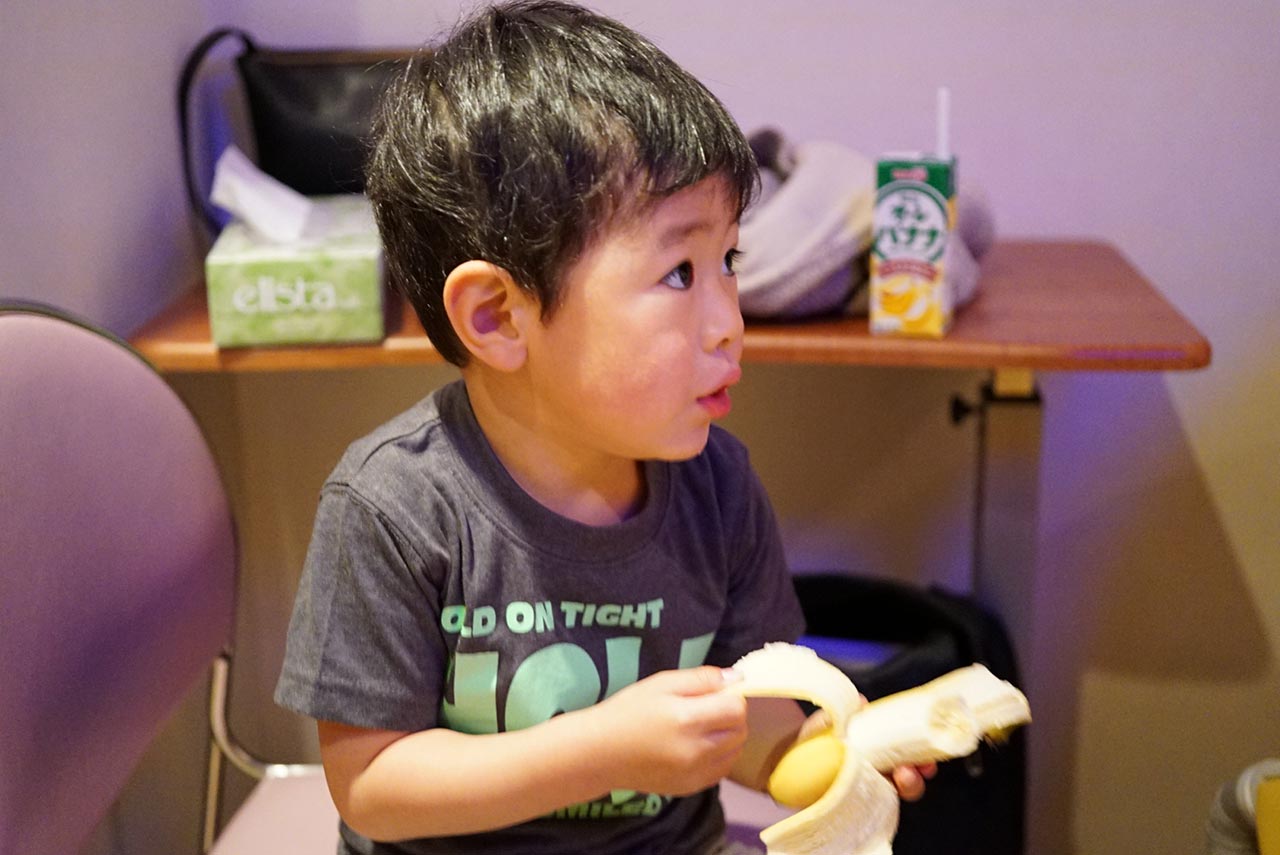 分娩室でバナナを食べながら、お母さんを励ましている息子。