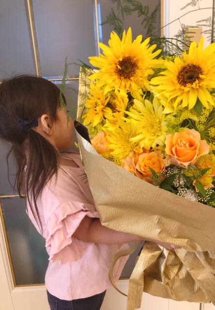 「父の日」のプレゼントの花束を抱える、3才になる娘さん