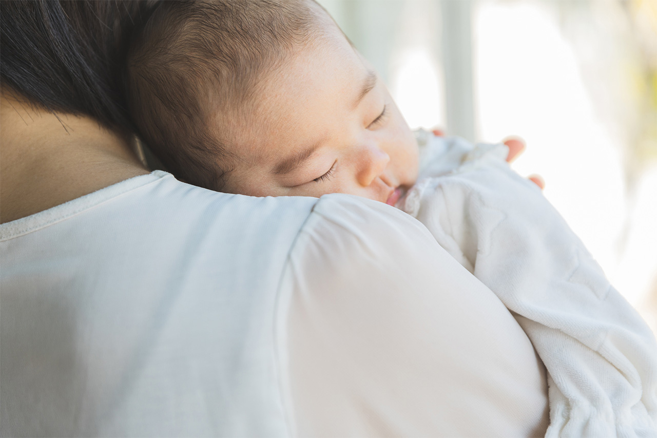 ママに抱っこされて寝ている赤ちゃんの画像